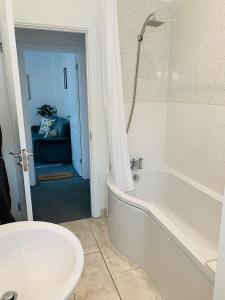 un bagno bianco con vasca e lavandino di Coastal Retreat Guest Suite a Minster Altre 14 foto