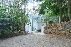 a stone wall in front of a white house at Bluevalley Estate - Three Bedroom Villa in Yercaud