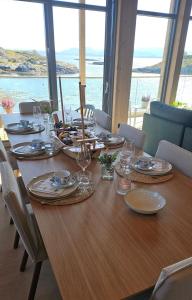 a wooden table with plates and wine glasses on it at Sjåen på Balsnes Gård in Hitra