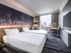 a hotel room with two beds and a desk at Novotel Bangkok Sukhumvit 4 in Bangkok
