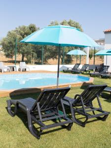 a pair of chairs and an umbrella next to a pool at Tavira Monte in Tavira