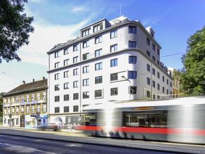 a bus driving past a tall white building at ibis Styles Wien Messe Prater in Vienna