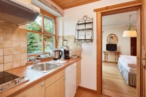 a kitchen with a sink and a window and a bed at Landsitz Römerhof - Hotel Apartments in Kitzbühel