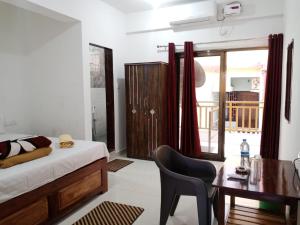 een slaapkamer met een bed, een bureau en een tafel bij Prakash Holiday Inn in Arambol +19 foto's