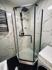 a glass shower in a bathroom with marble walls at Apartament in Tarnowskie Góry +11 photos