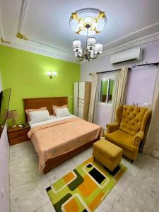 a bedroom with a bed and a chair and a chandelier at Samouraï Residence in Douala