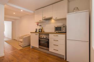 Central Lisbon Stay with Terrace في لشبونة: مطبخ بخزائن بيضاء وثلاجة بيضاء