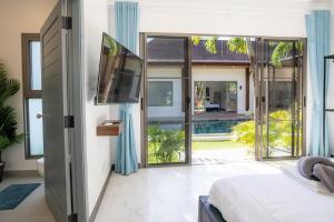a bedroom with a bed and a tv and sliding glass doors at villa Akala in Ban Saiyuan (1)