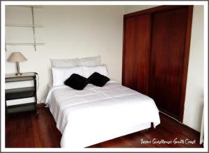 a white bed with two black pillows on it at Ingwe Guest House and Self Catering in Durban