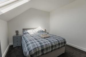 a bedroom with a bed with a plaid blanket at Hulliday City Centre Urban Apartment 3 in Hull