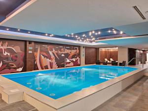 a large swimming pool in a building with a mural at ibis Styles Sarajevo in Sarajevo
