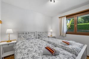 a white bedroom with two beds and a window at Arnica 14 - 6 pers - piscine in Nendaz +34 photos
