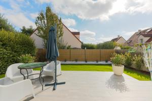 a patio with an umbrella and a table and chairs at Family Elegance - Comfort & Garden in Cormeilles-en-Parisis +7 photos