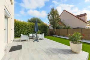 a patio with a table and chairs and an umbrella at Family Elegance - Comfort & Garden in Cormeilles-en-Parisis