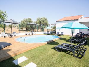 a swimming pool with chairs and umbrellas and a pool at Tavira Monte in Tavira