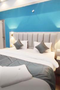 a large white bed with pillows and a blue wall at Seawood Homes in Calangute +3 photos