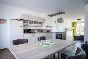 a kitchen and dining room with a wooden table and chairs at City Park Apartments - Hafenruhe in Großpösna