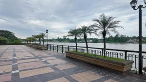 a walkway next to a river with palm trees at Kuching City Riverine Diamond by Bed and Brew Staycation in Kuching