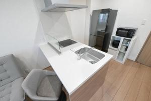 a white kitchen with a sink and a refrigerator at LA-CHIC Stay 大津 in Ozu