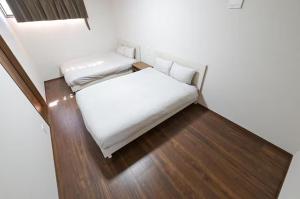 a small bedroom with a white bed and wooden floors at LA-CHIC Stay 大津 in Ozu