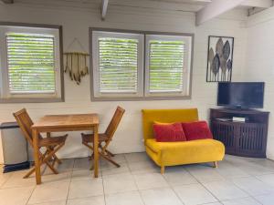a dining room with a table and a yellow chair and a television at Lodge 1 - Colibri - Jacuzzi Privé in La Plaine
