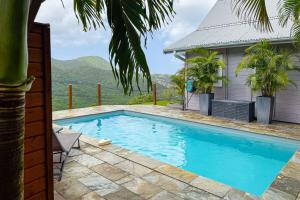 a swimming pool with a view of a house at Lodge 1 - Colibri - Jacuzzi Privé in Les Anses-dʼArlets