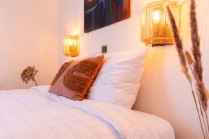 a bedroom with a bed with a pillow and two lights at BadHotel Noordwijk in Noordwijk