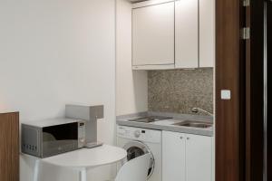 a kitchen with a washing machine and a microwave at Pale De Cz Condo in Busan