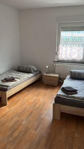 two beds in a room with wooden floors and a window at FeWo Neuenkirchen in Neuenkirchen