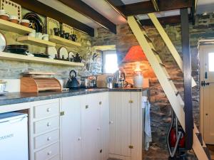 a kitchen with white cabinets and a stone wall at 1 Bed in Cape Clear Island oc-ii16739 in Lissarnona