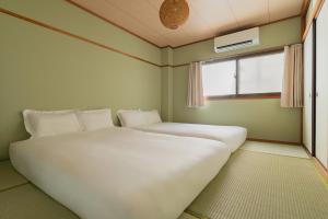 Dos camas en una habitación pequeña con ventana. en kinyo inn 2 101, en Osaka