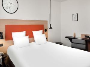 a bedroom with a large white bed and a desk at Hôtel ibis Styles Montargis Arboria in Pannes
