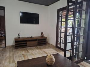 ein Wohnzimmer mit einem Flachbildfernseher an der Wand in der Unterkunft Casa praia fortaleza pé na areia in Ubatuba