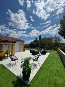 a patio with chairs and a table and grass at Villa Maeva Florensac in Florensac