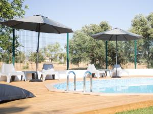 a swimming pool with umbrellas and chairs and a swimming pool at Tavira Monte in Tavira