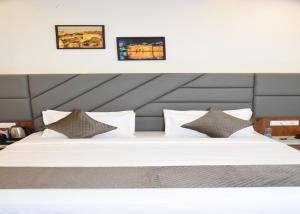 a large white bed with three pictures on the wall at Hotel Imperial in Dabok +40 photos