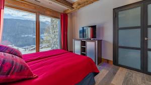 Schlafzimmer mit einem roten Bett und einem großen Fenster in der Unterkunft MGM Hôtels & Résidences - Le Chalet Apsara in Méribel