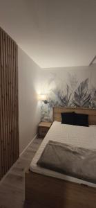 a bedroom with a bed and a wall with plants on it at Apartamenty Dabrowka Plus - w lesie, prywatny parking, park, sauna, miejsce grillowe in Jelenia Góra