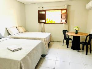 a room with two beds and a table and a window at Pousada sousa Residencial Qrt 3 in Sousa