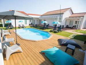 a swimming pool on a wooden deck with chairs and umbrellas at Tavira Monte in Tavira
