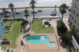 a view of a swimming pool and a parking lot at Cap d Azur beachfront apartment in Strand