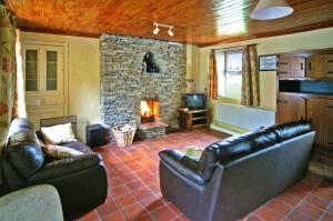 sala de estar con muebles de cuero y chimenea de piedra. en 4 Bed in Portmagee oc-i164, en Lateeve