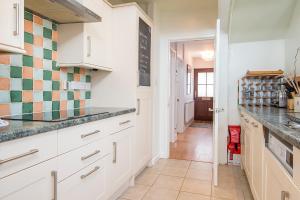 a kitchen with white cabinets and green and white tiles at Cherry Tree House in Haverfordwest