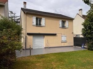 ein Haus mit einer Garage und einer Auffahrt in der Unterkunft Maison Familiale au coeur d'aulnay sud, proche gare, aéroport CDG, Parc des expositions in Aulnay-sous-Bois