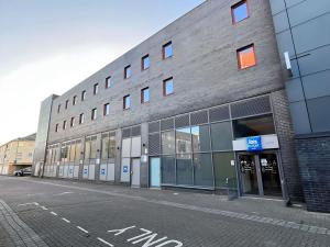 un gran edificio de ladrillo con ventanas de cristal en una calle en ibis budget Swindon, en Swindon