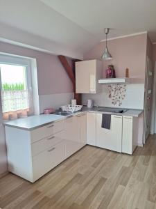 una cucina bianca con armadi bianchi e pavimenti in legno di Apartament Platynowy - Malbork a Malbork Altre 9 foto