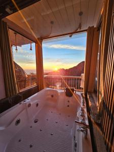 a bath tub in a room with a view of the sunset at Panoramic Jacuzzi Suite with huge Balcony & Swing in Mussoorie +9 photos