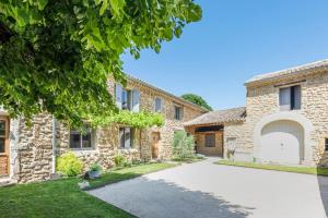 an exterior view of a stone house with a driveway at La Bastide du Père Mathieu Jacuzzi couvert et Piscine in Suze-la-Rousse