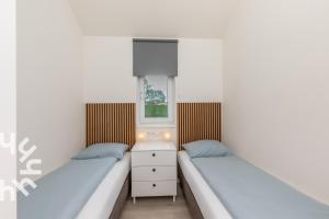 two beds in a small room with a window at Gezellige vakantiewonig gelegen in Grijpskerke in Grijpskerke