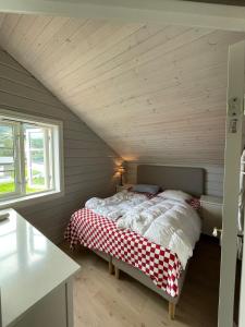 een slaapkamer met een bed met een rood-witte deken bij House with oceanview in Stryn